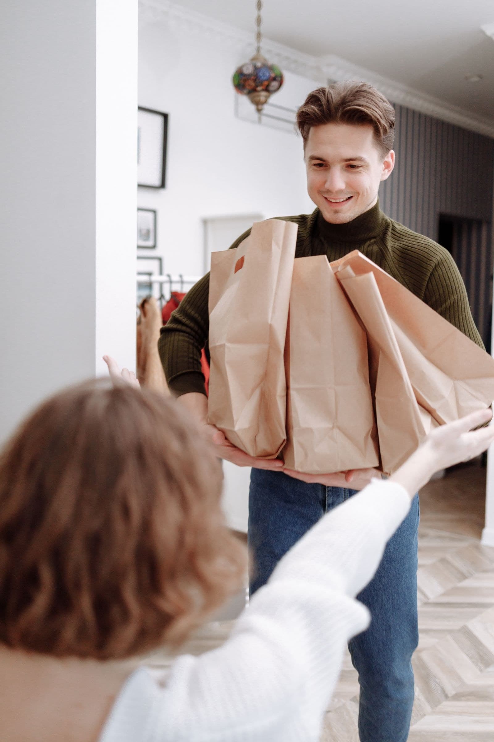 A helper arriving at the door with paper bags of shopping
