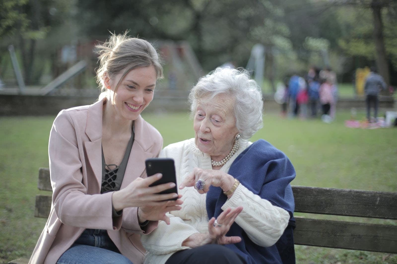 A helper and an older woman sitting together on a park bench
