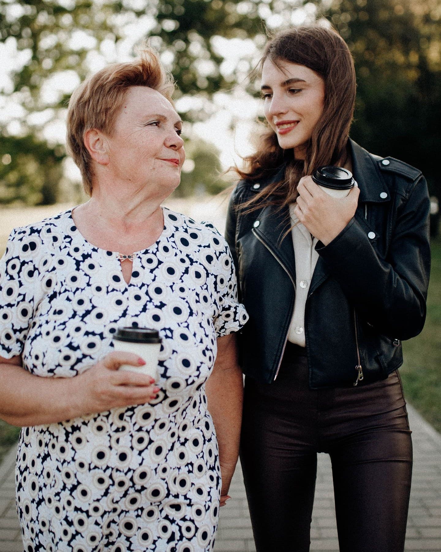 A helper and an older woman walking together in a Sheffield park